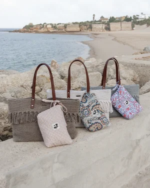 Bolsos de playa sobre unas rocas y con el fondo de una playa